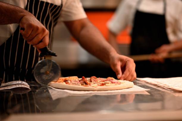 istock Pizza cut by chef in restaurant kitchen 1557473505