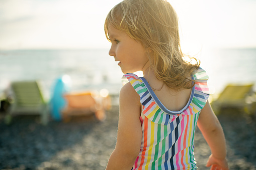 Cute little girl enjoying sunset near the sea on beach holidays