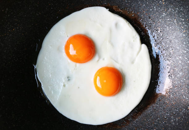 vista superior do par de ovos ensolarados sendo fritos em uma panela - sunny side up - fotografias e filmes do acervo
