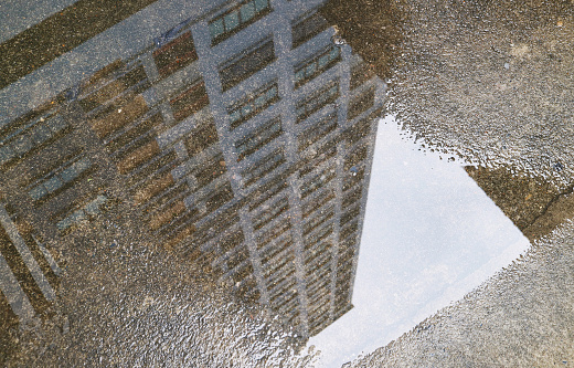 Closeup of high buildings reflecting on the puddle