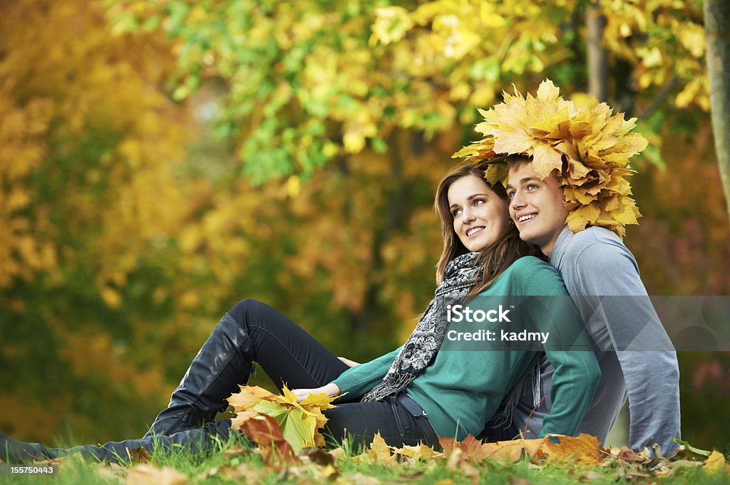 Couple at autumn outdoors Two Smiling young attractive people with autumn maple leaves in park at fall outdoors date Adult Stock Photo