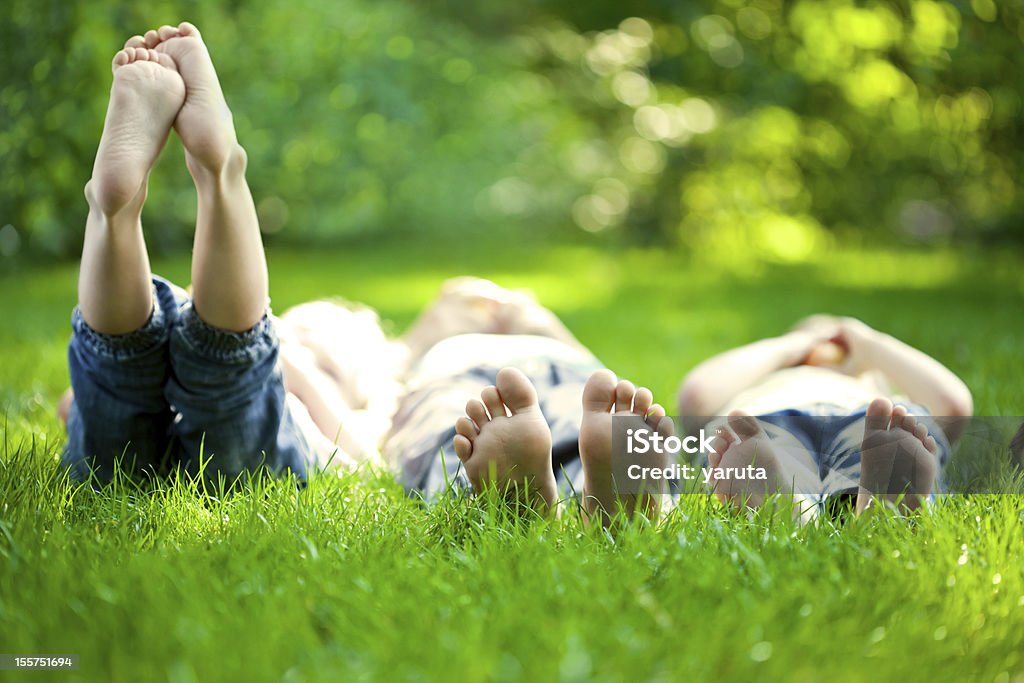 Selective focus three children in grass at picnic Group of happy children lying on green grass outdoors in spring park. Child Stock Photo