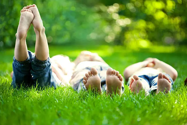 Group of happy children lying on green grass outdoors in spring park.