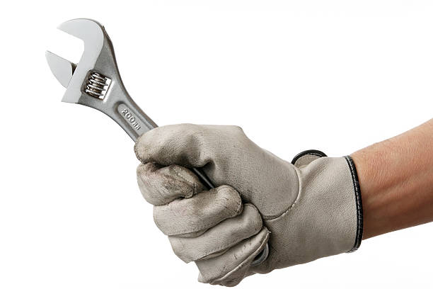 Isolated shot of working hand with wrench against white background Working hand with wrench isolated on a white background. adjustable wrench photos stock pictures, royalty-free photos & images