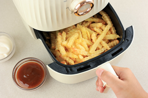 Cooking French Fries Potato with Airfryer, Less Oil Cooking Concept. Female Hand. Female Hand Take Airfryer Tray, Top View