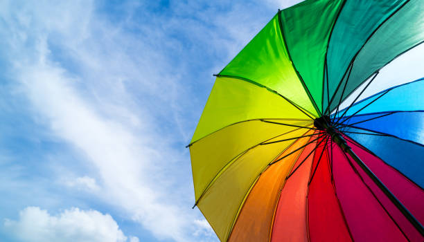 istock Colorful rainbow umbrella on blue sky background. LGBT, Pride Month, diversity, Sunprotect Concept. 1557538763