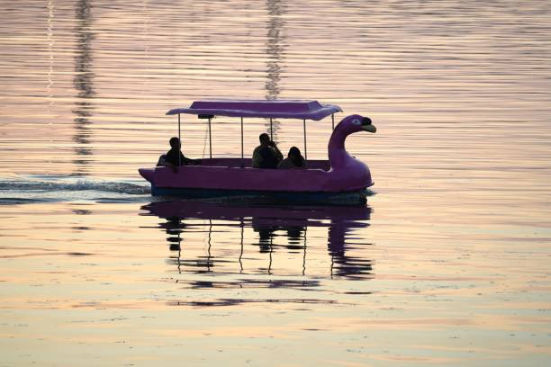 Makassar, Indonesia - July 15, 2023: A number of tourists are riding duck boats enjoying the beach and sunset