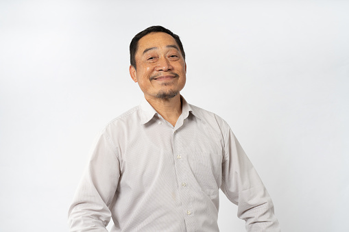 Asian mature man with studio portrait, showcasing authentic expressions and genuine emotion. looks at camera on white background, aged gracefully with wisdom and characterful wrinkles.