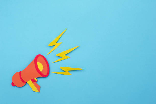 istock Loudspeaker announcing promotions on blue background made of paper cut. 1557578291