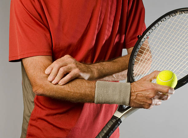 tennis player massaging elbow stock photo