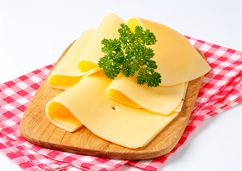 folded slices of fresh cheese with a parsley on a wooden cutting board and a chequered cloth