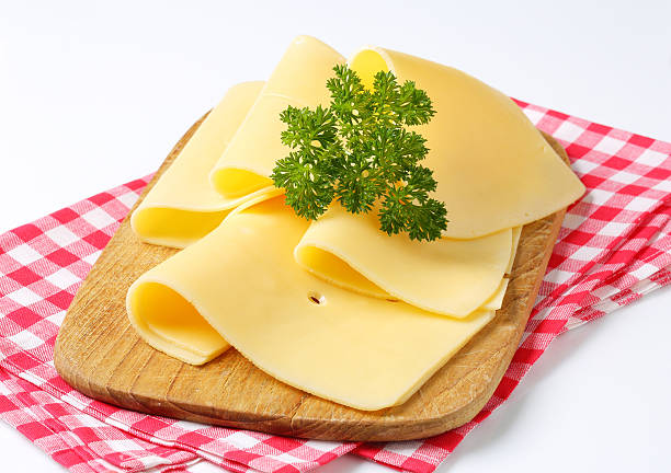 slices of cheese on a cutting board folded slices of fresh cheese with a parsley on a wooden cutting board and a chequered cloth edam stock pictures, royalty-free photos & images