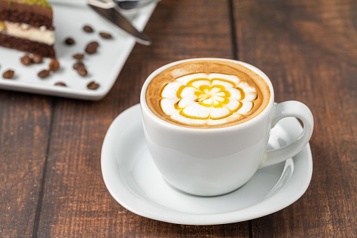Patterned cappuccino coffee in a white porcelain cup on a wooden table