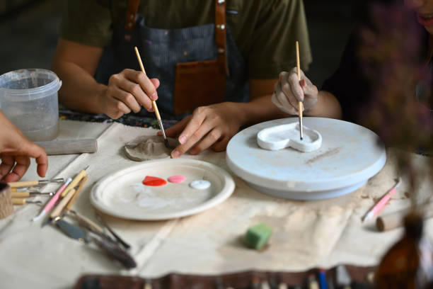 istock Image of young asian man enjoying creative process, creating handmade ceramics in pottery workshop. 1557654234