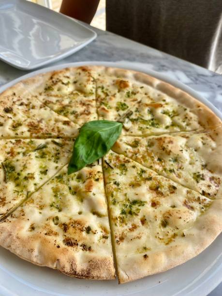 Delicious Gluten Free Round Garlic Pizza Bread Cut Into Triangular Slices with Fresh Basil Leaf on Top Food from Bianco Restaurant in Playa de Las Americas in Tenerife, Spain