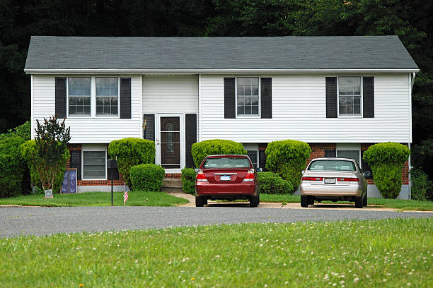 Closed windows on a white brick wall with grassy curb and parking lot in front