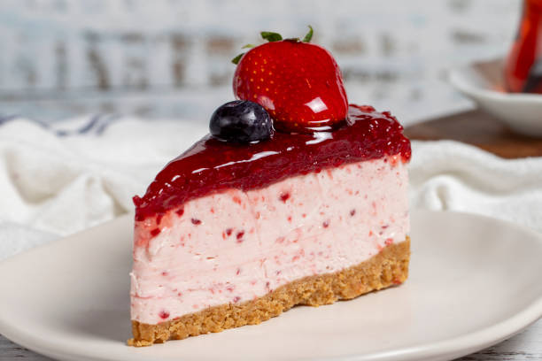 istock Fruit cake slice. Cheesecake slice with blackberry sauce on wood background. Close up 1557658004