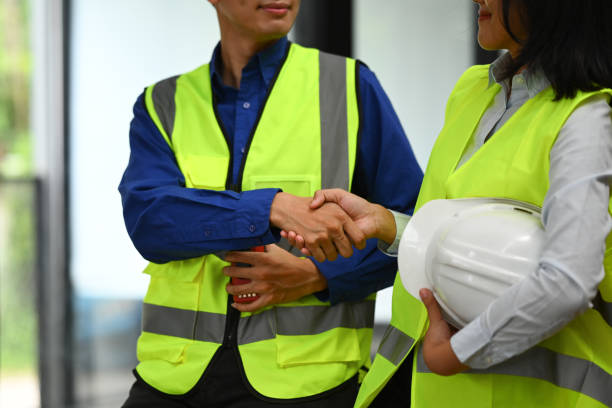 istock Engineer teams holding helmets and shaking hands after successful meeting in the office. 1557660208