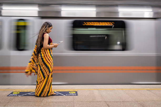 istock Indian girl using a digital tablet at metro station, India 1557667437