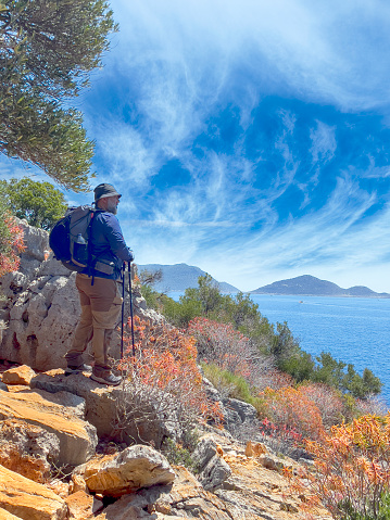 Male Hiker walking by Lycian Way trail along wild beach and mountains in Turkey