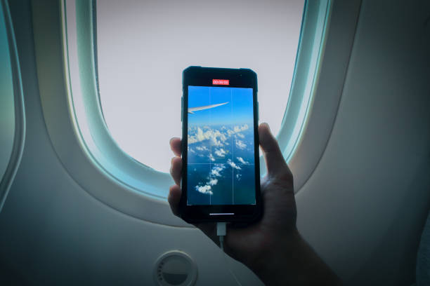 istock Asian boy is holding mobile phone to record sky view from airplane window 1557676829