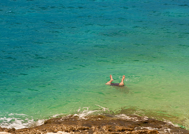 Legs of a man jumping into sea water stock photo