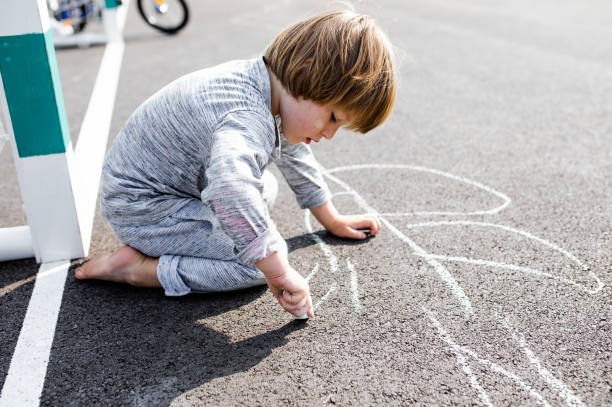 istock Young boy doodling the asphalt with a chalk 1557692493