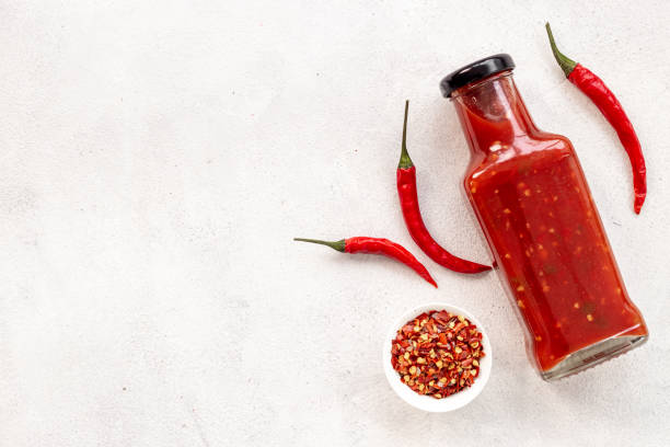 istock Red chili pepper sauce in bottle with ripe hot pepper 1557713143