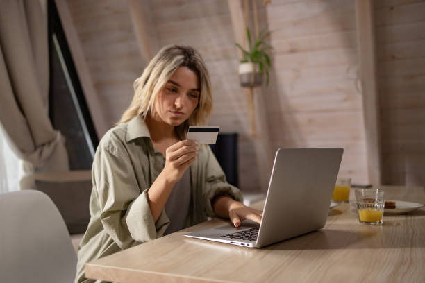 istock Young woman using credit card for home shopping over laptop. 1557714312