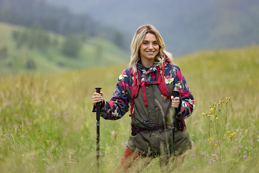 Happy female backpacker enjoying in her hike in nature and looking at camera.