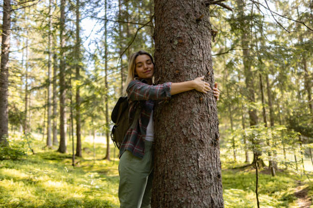 istock Carefree woman hugging a tree in the forest. 1557718094