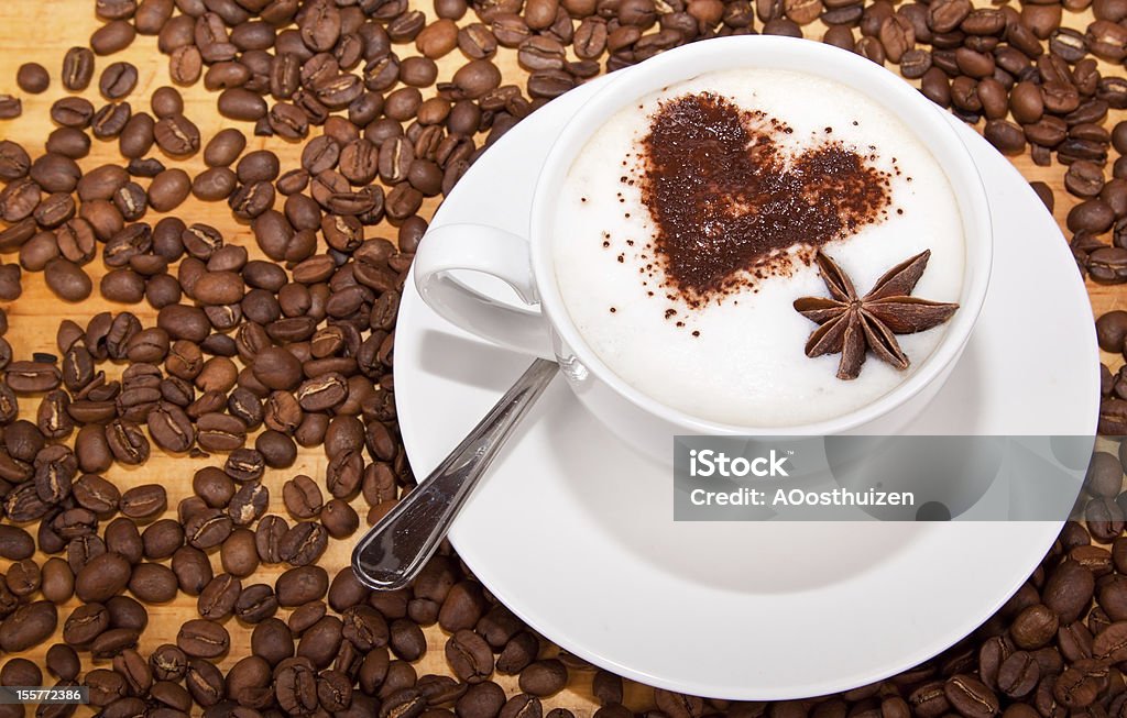 Frothed coffee with heart shape and star aneceed Frothed milk coffee with brown heart shape, star aneceed and coffee beans scattered around Brown Stock Photo