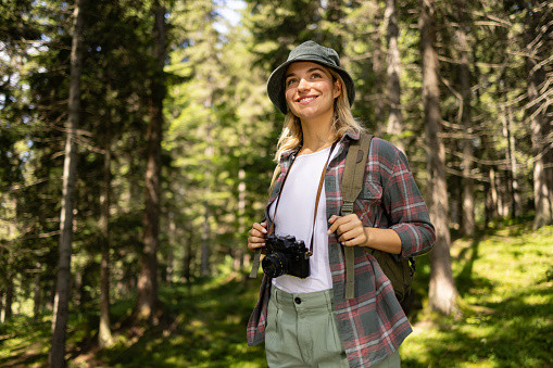 Happy female backpacker enjoying while day dreaming in the forest.