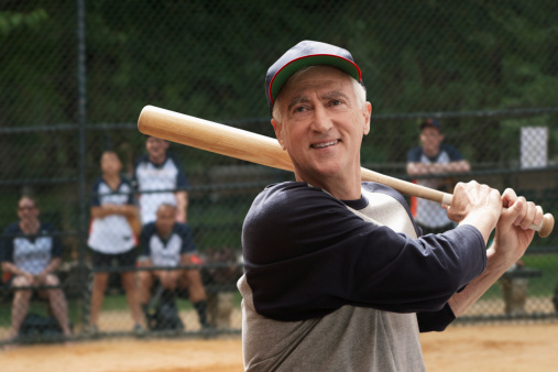 Full length profile shot of a mature man with a baseball bat giving a ball to a boy isolated on white background