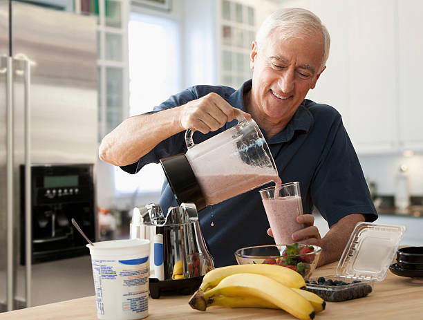 Senior man pouring glass of fruit smoothie New Jersey smoothie photos stock pictures, royalty-free photos & images