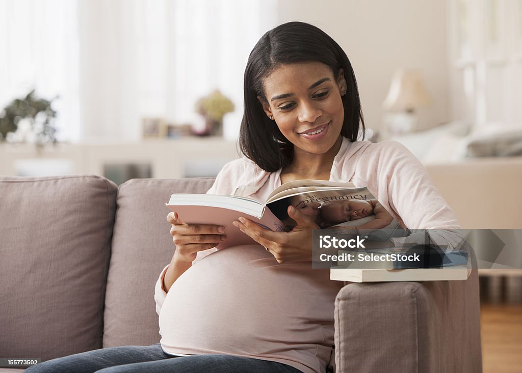 Mujer embarazada leyendo un libro sentado - Foto de stock de Embarazada libre de derechos