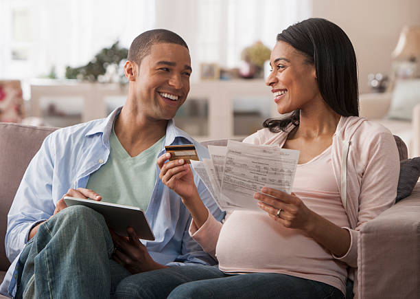 młodzi rodzice się z rachunki i tablecie - human pregnancy finance mixed race person holding zdjęcia i obrazy z banku zdjęć
