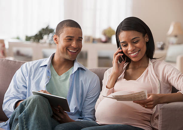 若い両親のために、電子タブレット - human pregnancy finance mixed race person holding ストックフォトと画像