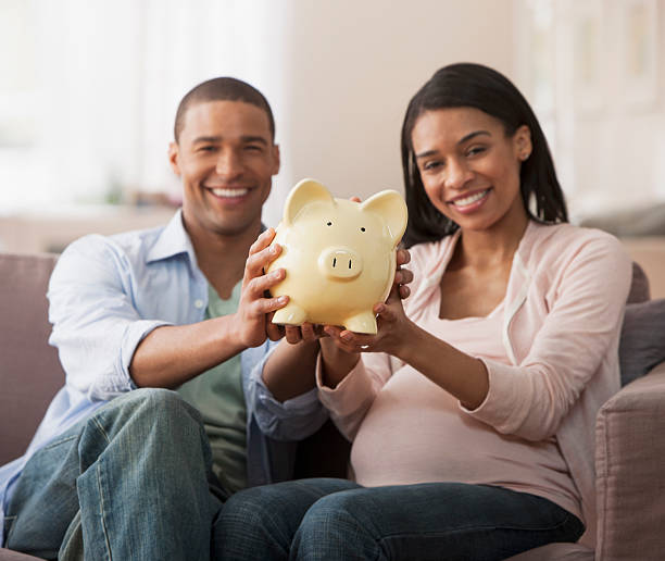 若い両親を持つピギー銀行 - human pregnancy finance mixed race person holding ストックフォトと画像