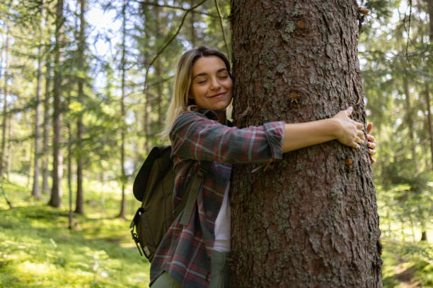 istock Young carefree woman enjoying while hugging a tree in the forest. 1557735451