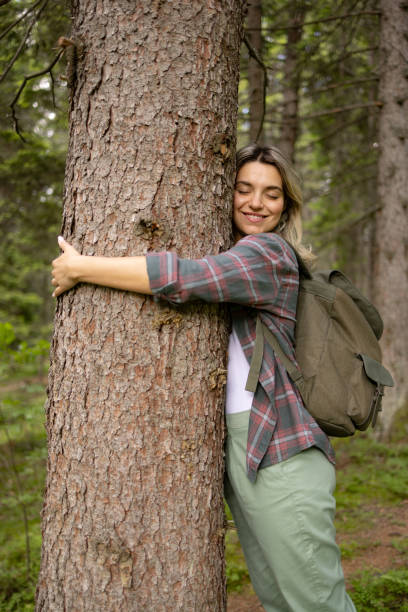 istock Young happy woman enjoying while hugging a tree in the forest. 1557735453