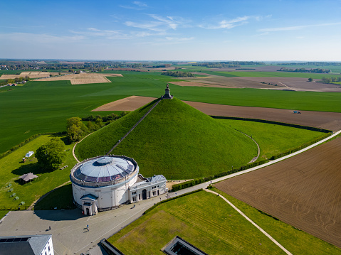 Aerial view farm field, Lion's Mound, Battle field, Napoleon, Waterloo, Belgium, green and sky, season. Aerial View at the Waterloo Hill with the statue of the lion of Memorial Battle of Waterloo, Belgium. Aerial landscape view shot by a drone.