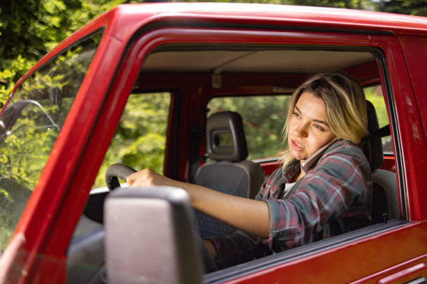 istock Careless woman communicating over cell phone while driving a car. 1557744711