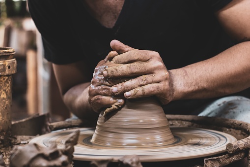 Close-up of a skilled artisan potter's hands carefully crafting a unique vase from clay