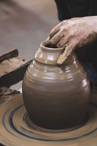 Closeup of an artisan's hands as they craft a vase from clay
