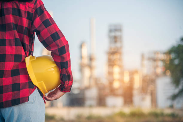 istock Woman worker hands holding hardhat yellow work helmet Construction Engineer. Refinery woman worker oil petro industry hand hold yellow worker helmet hard hat. Refinery industry engineer manufacture 1557750816