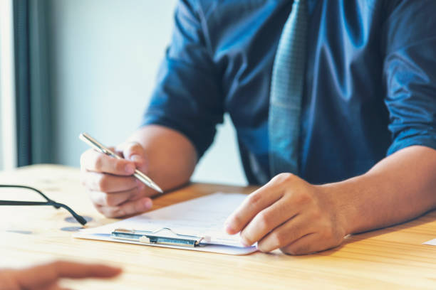 istock Closeup businessman hands working on finance business document reading report paperwork spreadsheet using laptop at office desk. Man hands write on office note look at financial graph chart document 1557752503