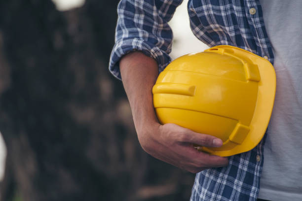 istock Engineer man hands holding hardhat white work helmet hard hat for Civil Construction Engineering. Construction engineer man in safety suit hold white work helmet hard hat on hands at Construction Site 1557752545