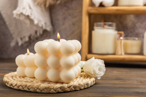 istock Soy wax bubble candle on a textured table. Interior decor with handmade burning candle and dried flowers. Hygge home decoration concept and aromatherapy. 1557765570