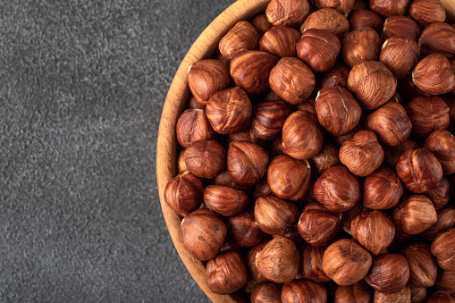 A bowl full of peeled hazelnuts  on black background,overhead view